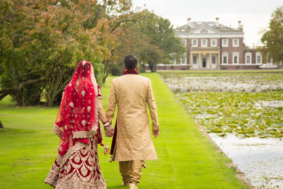 Asian wedding couple holding hands walking down to Boreham house