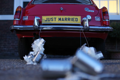 close up view of just married car with tins hanging off