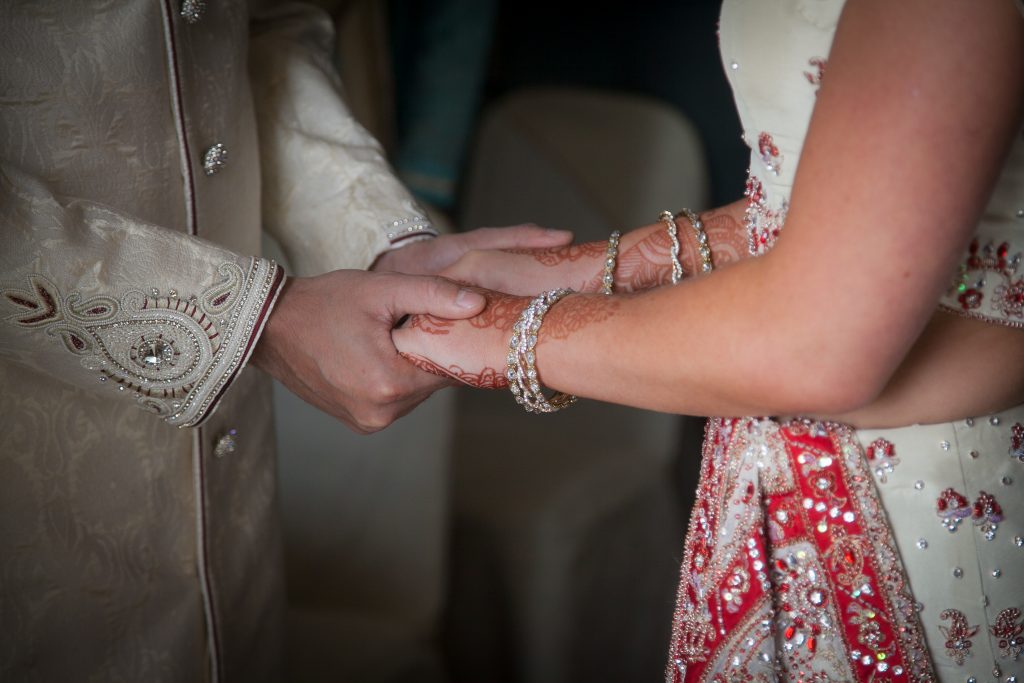Asian wedding couple holding hands. Bride with henna on her hand and bangles