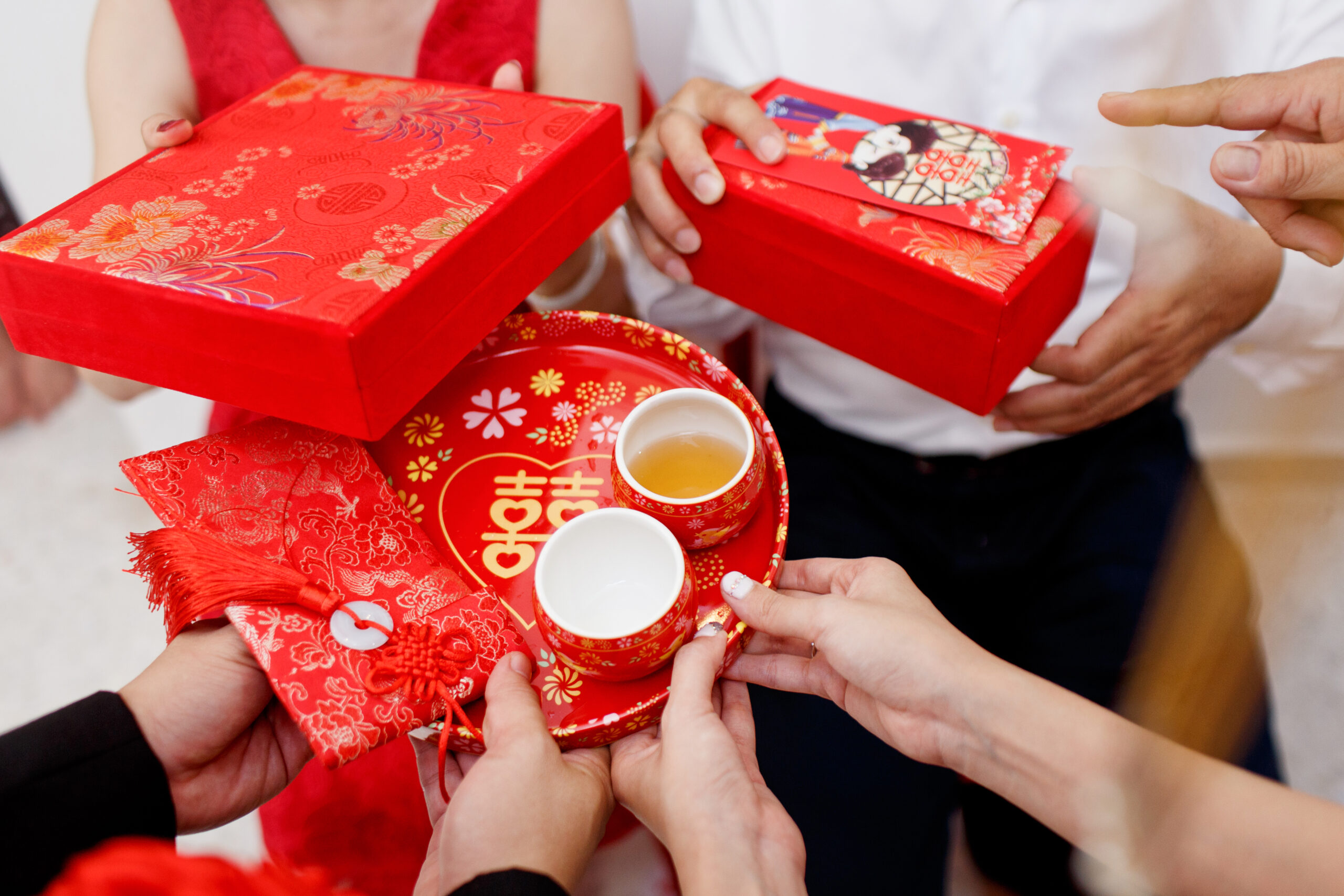 Wedding couple holding red envelope packet, tea and small gifts